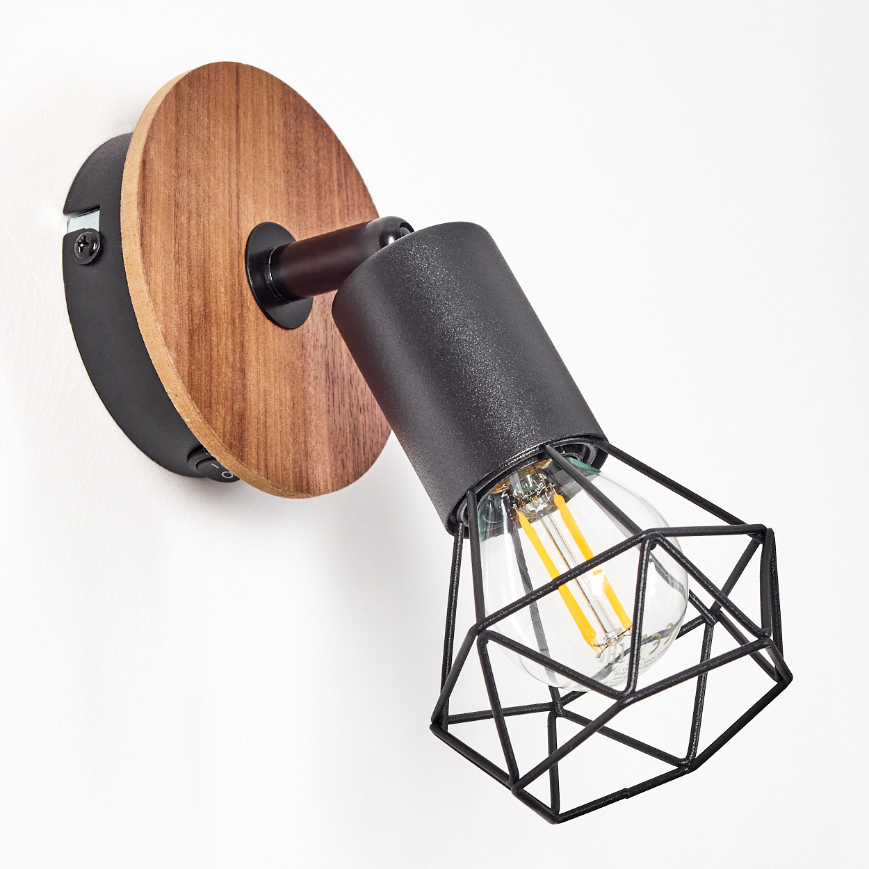 Wand-Spotlight mit einem schwarzen Käfig, einem Holzsockel und einer sichtbaren Glühbirne. Das Licht ist an.