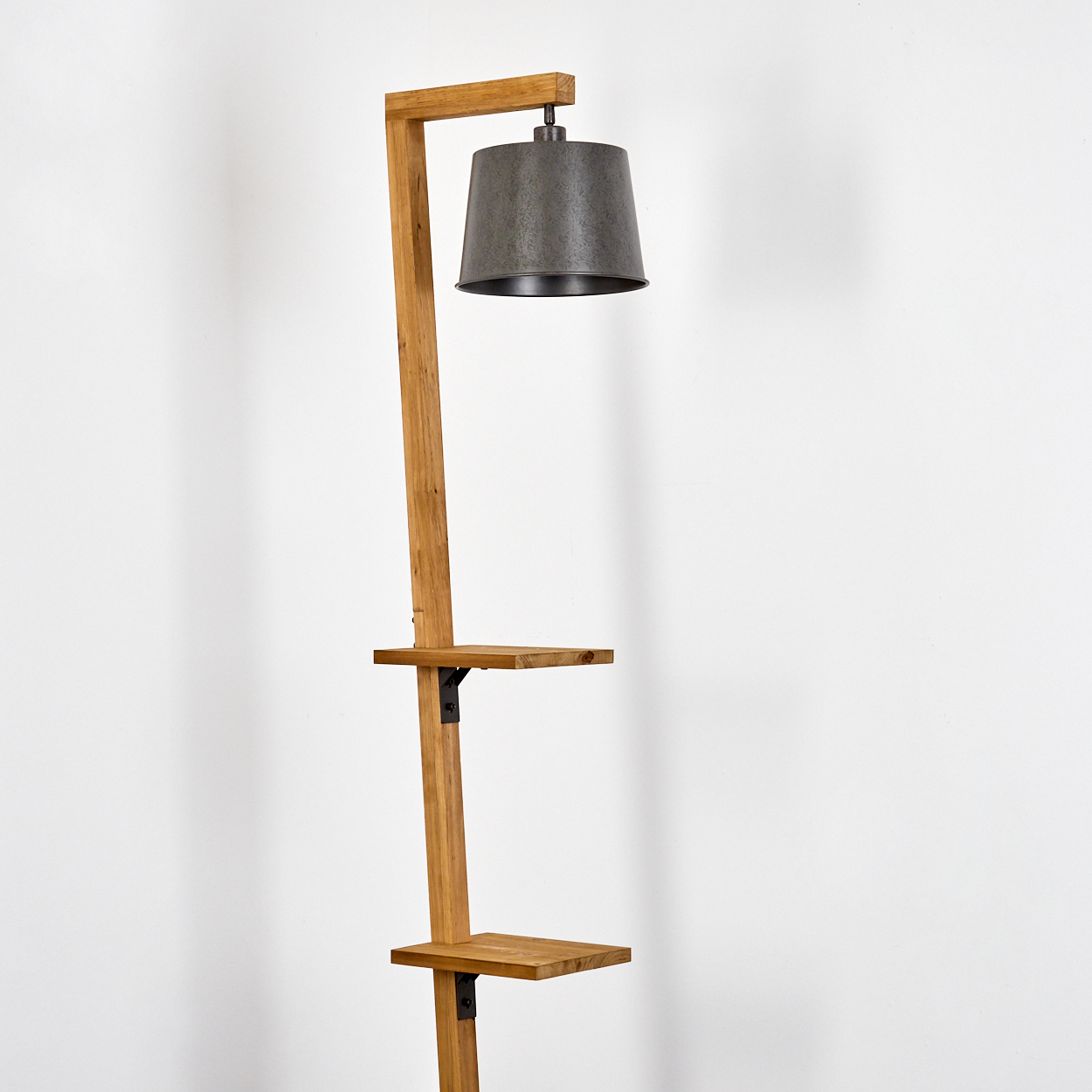 Stehlampe aus Holz mit Lampenschirm aus Metall und zwei Holzregalen.