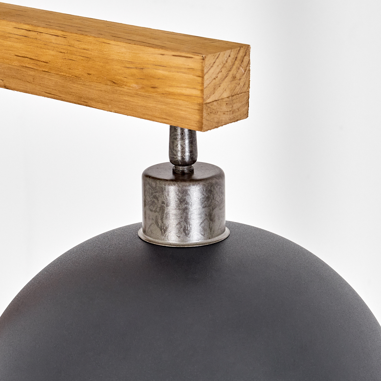 Nahaufnahme einer schwarzen Lampe mit Holzarm. Das Licht hat eine kuppelförmige goldene Innenseite.