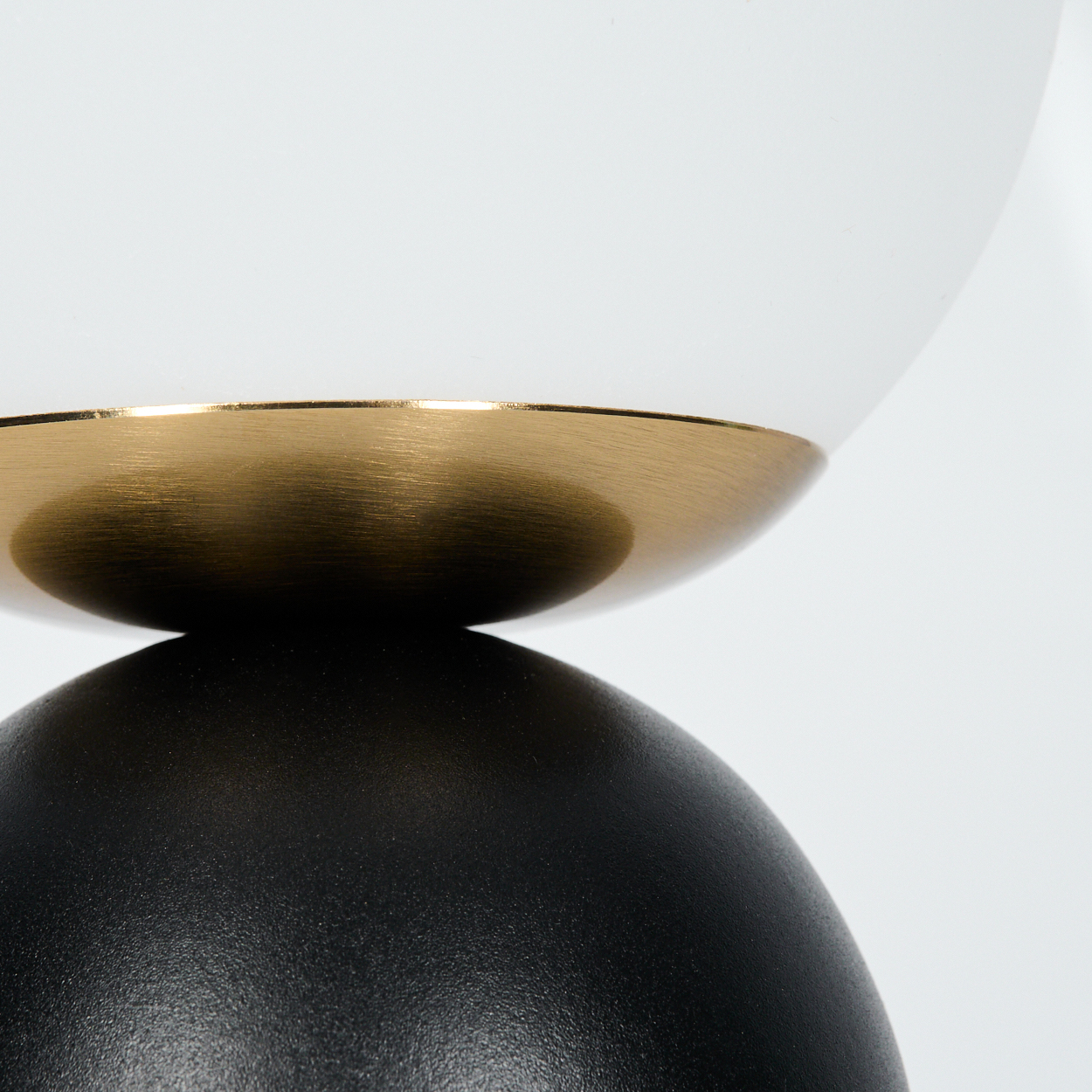 Eine schwarz-weiße Lampe mit einem goldenen Band. Die Lampe besteht aus zwei Teilen, einem schwarzen Sockel und einem weißen Oberteil.