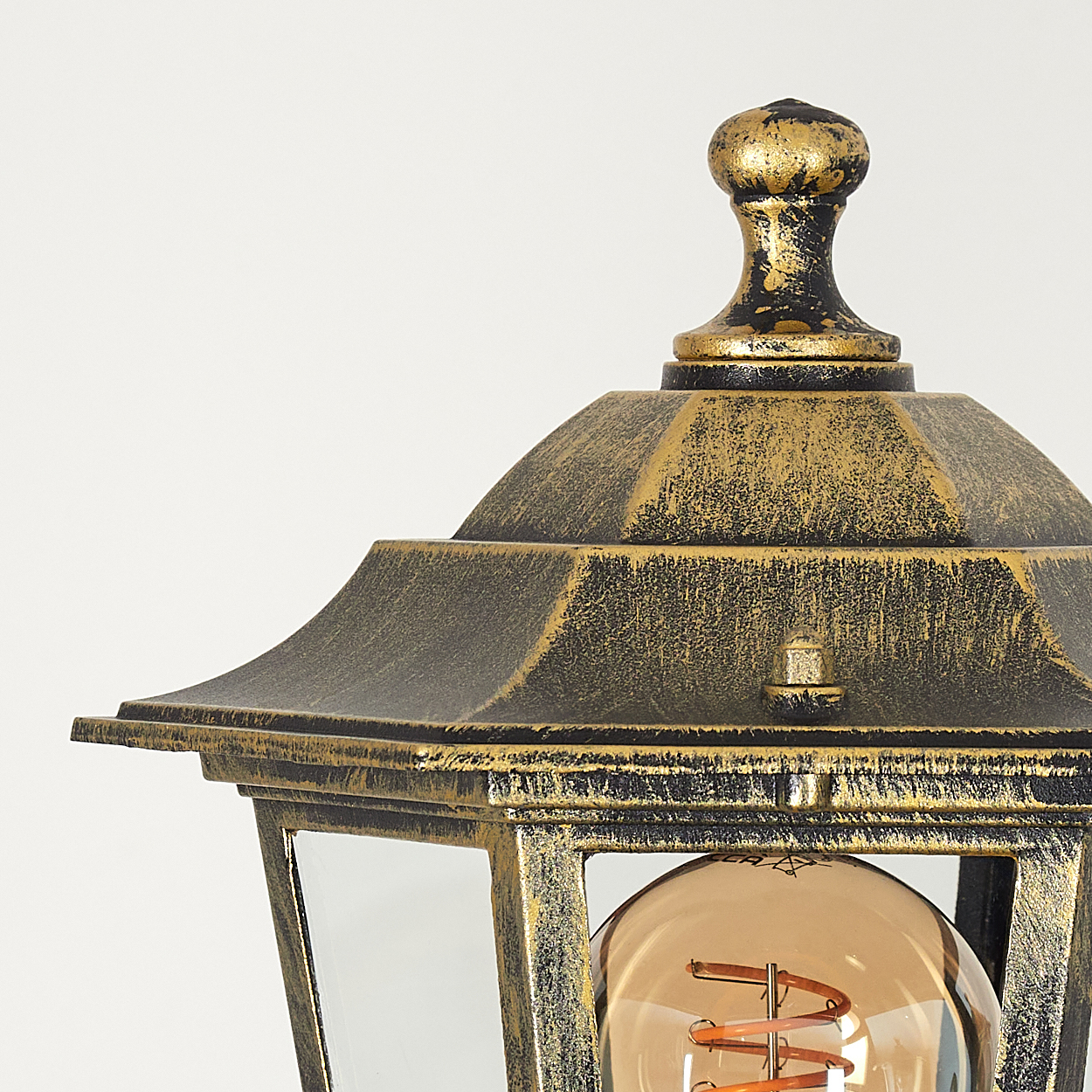 Nahaufnahme einer goldenen Außenlampe. Glasscheiben mit Glühbirne im Inneren. Schwarz und Gold.