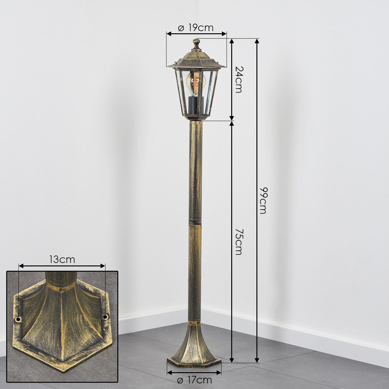 Eine Außenlampe mit Bronze-Finish, klarem Glas und sechseckiger Oberseite steht auf einer grau gefliesten Oberfläche, wobei Maße angegeben sind.