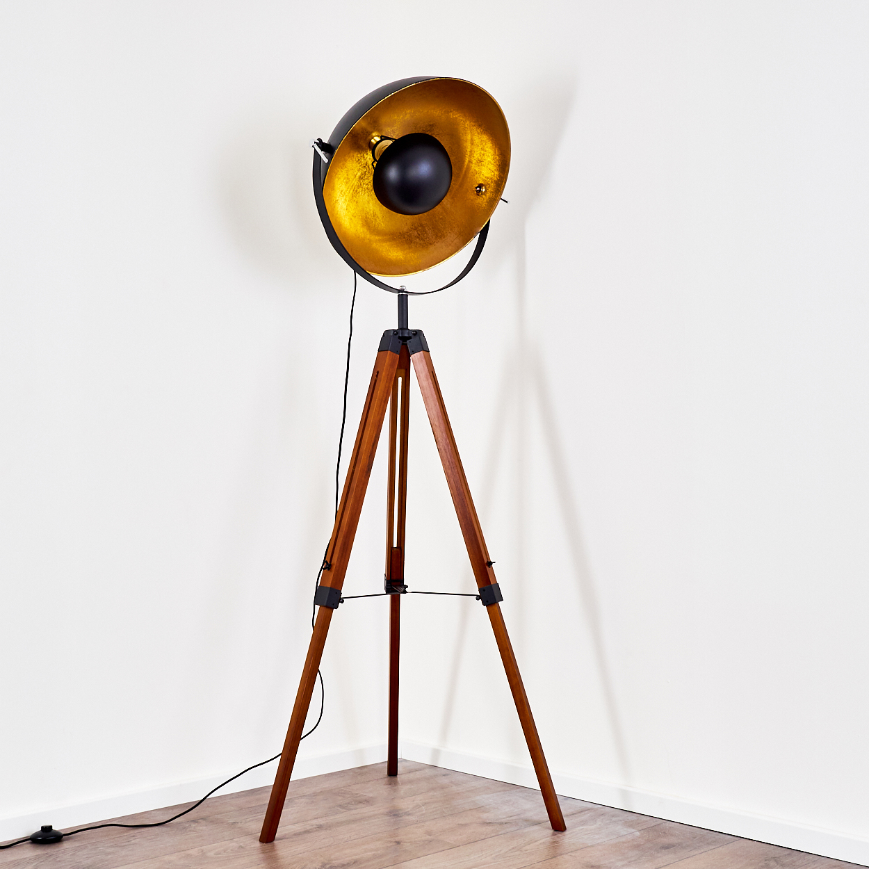Hohe Stehlampe mit Holzstativ und schwarzem, goldenem Lampenkopf.
