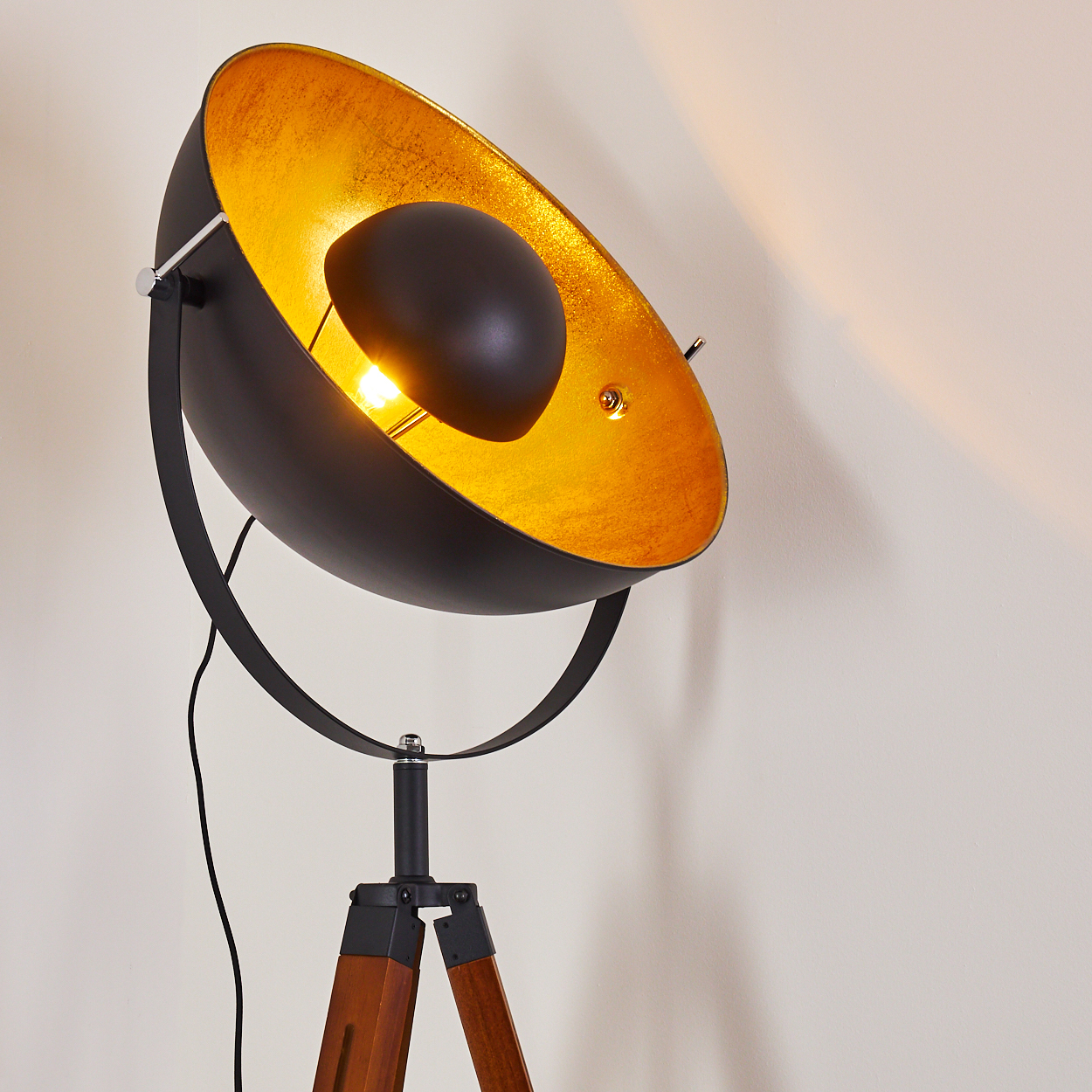Eine schwarz-goldene Stehlampe. Die Lampe hat einen schwarzen Schirm und ein goldenes Innenleben.