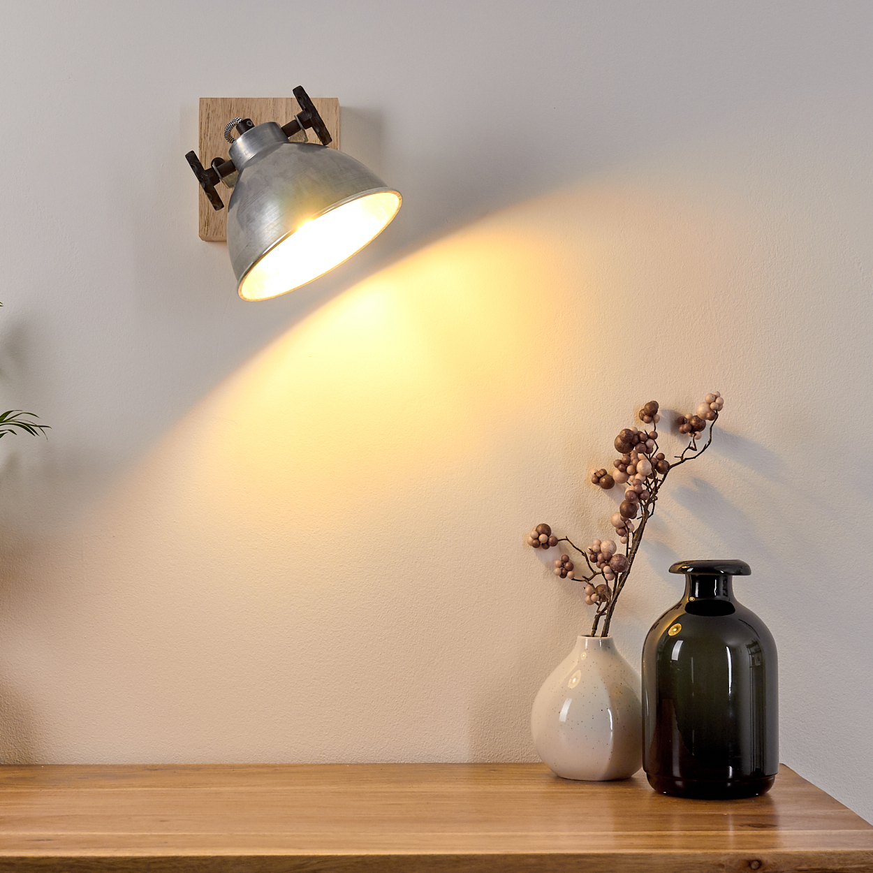 Industrielle Wandlampe auf Holzoberfläche, wirft Licht auf eine Wand.