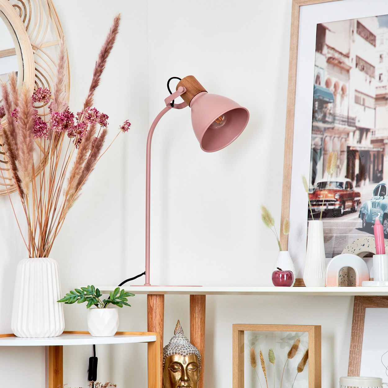 Rosa Schreibtischlampe auf einem weißen Regal, mit Dekorationen und einem Bilderrahmen im Hintergrund.