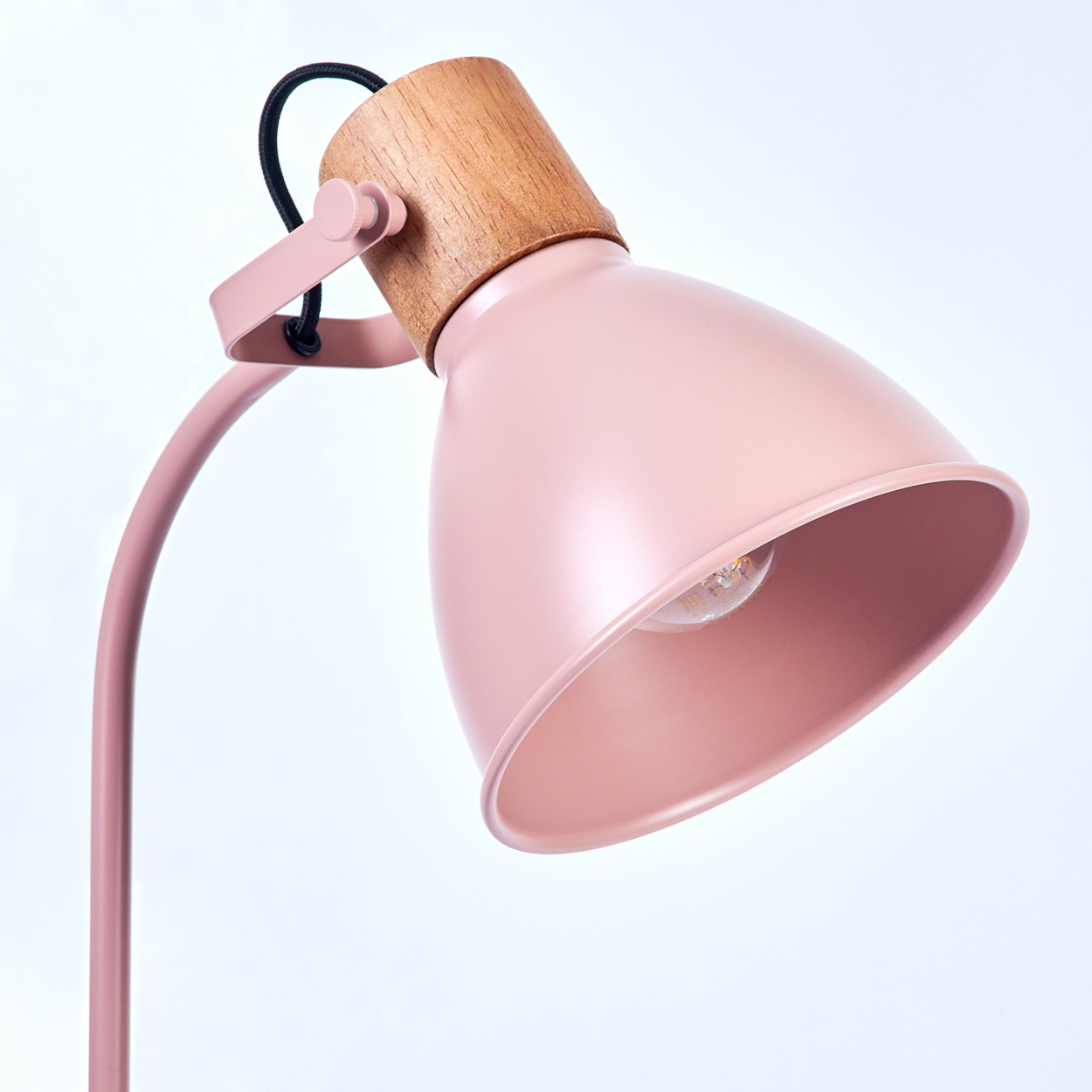Eine rosa Schreibtischlampe mit einem Holzakzent, die ihr minimalistisches Design vor einem schlichten weißen Hintergrund zeigt.