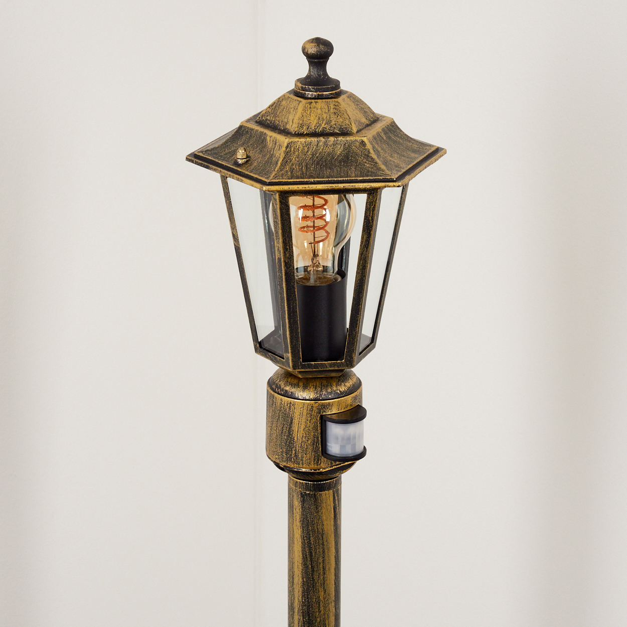 Nahaufnahme einer Außenlampe, goldfarben, mit Glühbirne. Sie hat einen Bewegungssensor.
