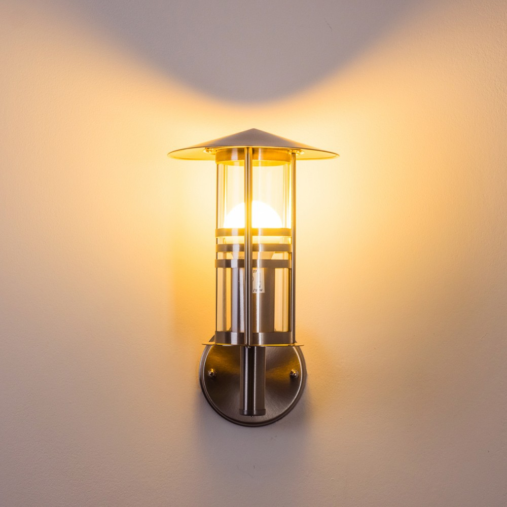 Eine silberne Wandlampe mit Licht, an einer hellen Wand montiert.