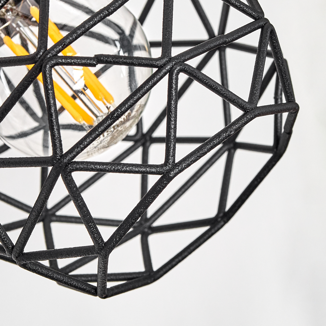 Nahaufnahme einer schwarzen geometrischen Leuchte mit einer sichtbaren Glühbirne und gelben Filamenten.
