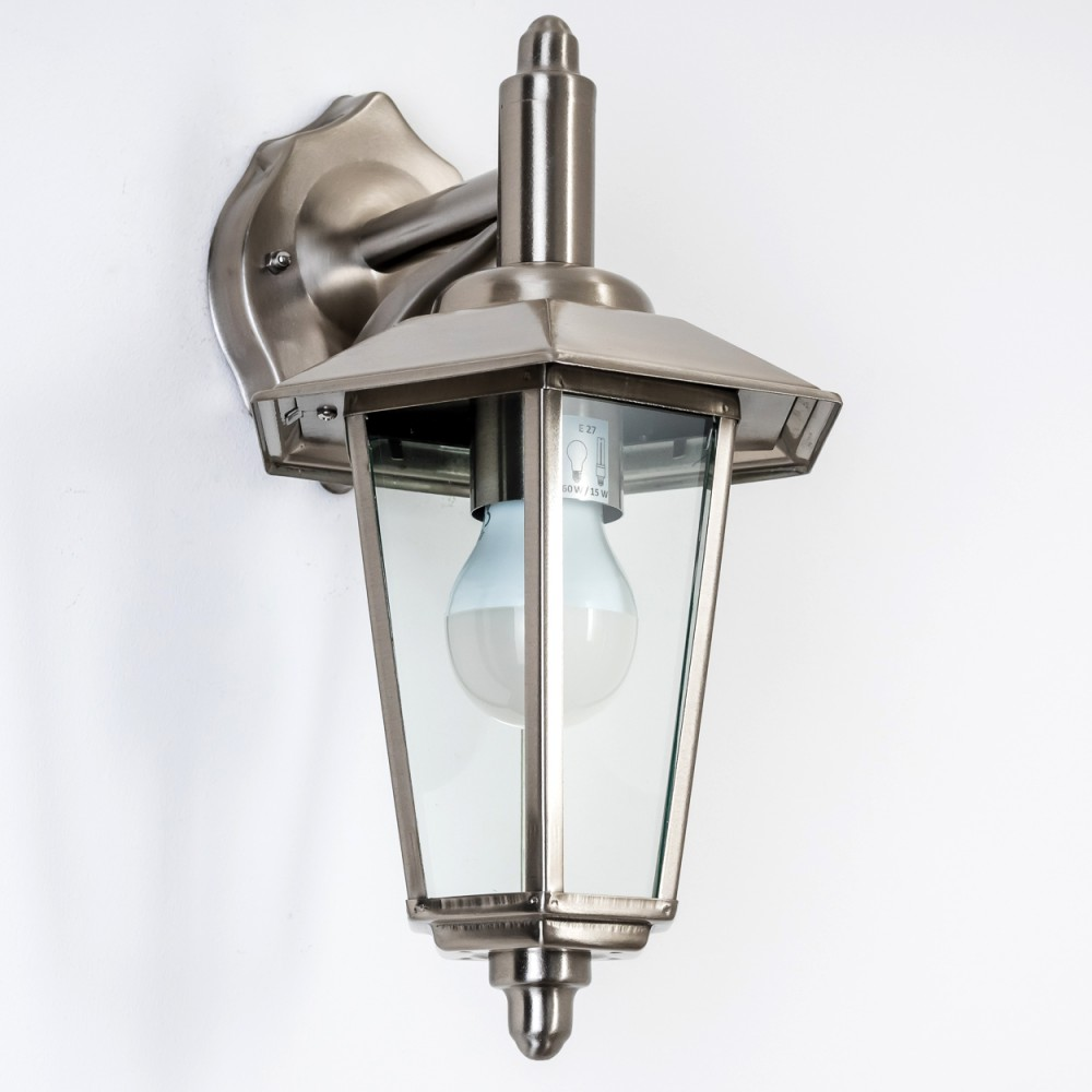 Eine wandmontierte, silberne Außenlampe mit Glasgehäuse. Sie hat eine Glühbirne und befindet sich vor einer weißen Wand.