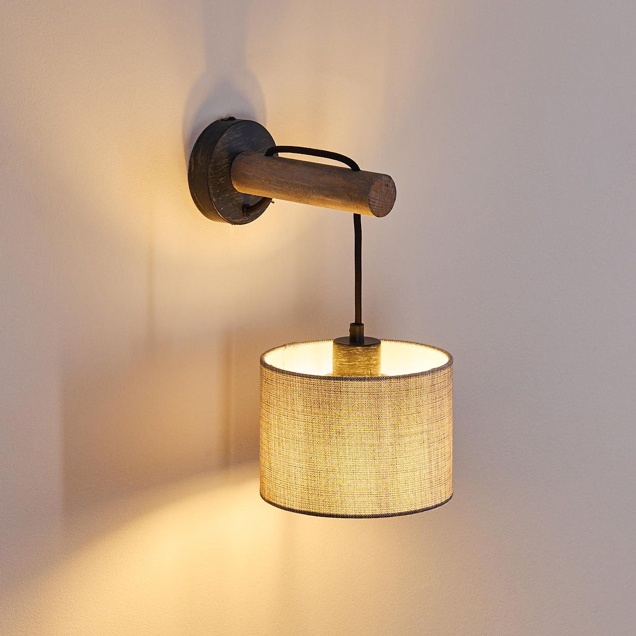 Wandleuchte mit Holzbogen und Stoffschirm. Das Licht ist an.