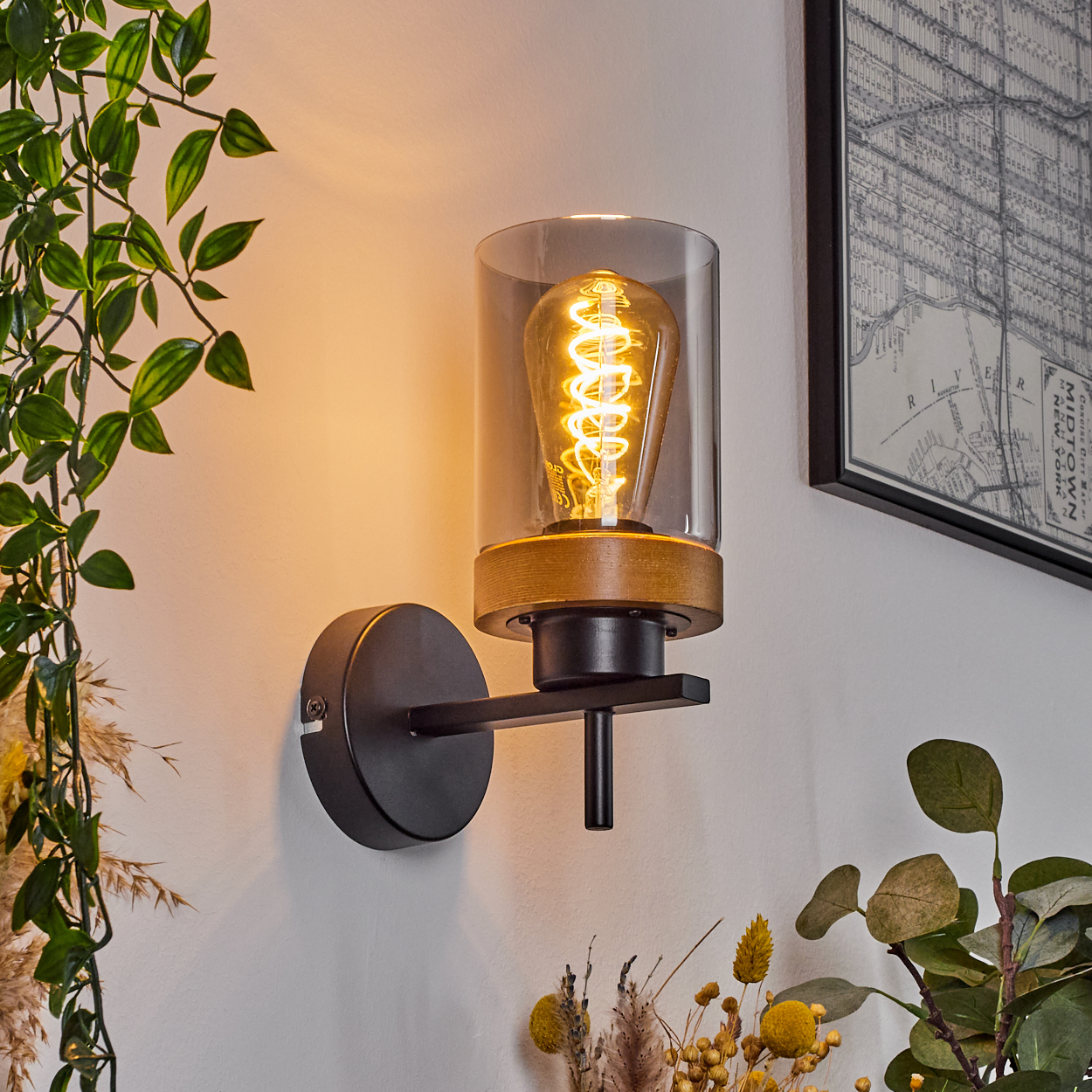 Eine schwarze Wandlampe mit Holzakzent und einem klaren Glaszylinder. Eine Edison-Glühbirne ist innen.