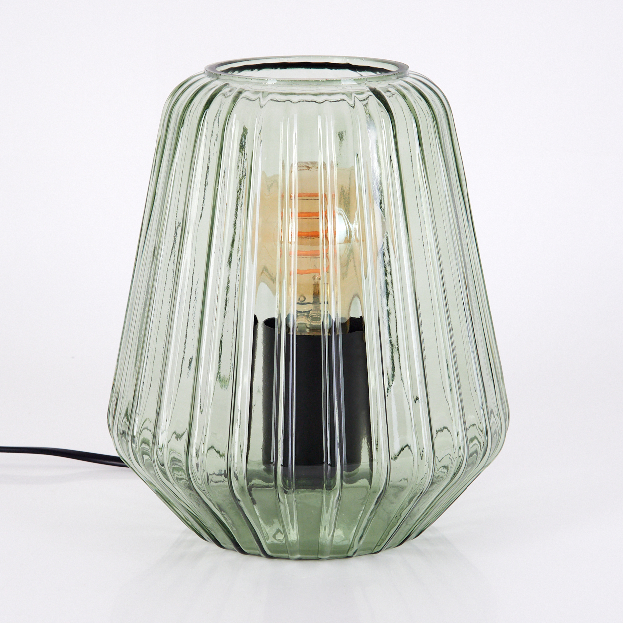 Grüne Glastischlampe mit einer Glühbirne. Die Lampe hat eine gerippte Textur.