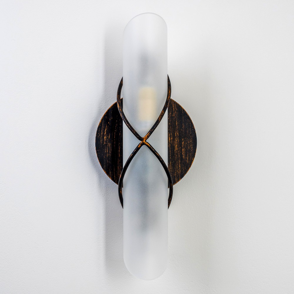 Eine Wandlampe mit bronzefarbenem Rahmen und einem Schirm aus Milchglas, an einer weißen Wand montiert.