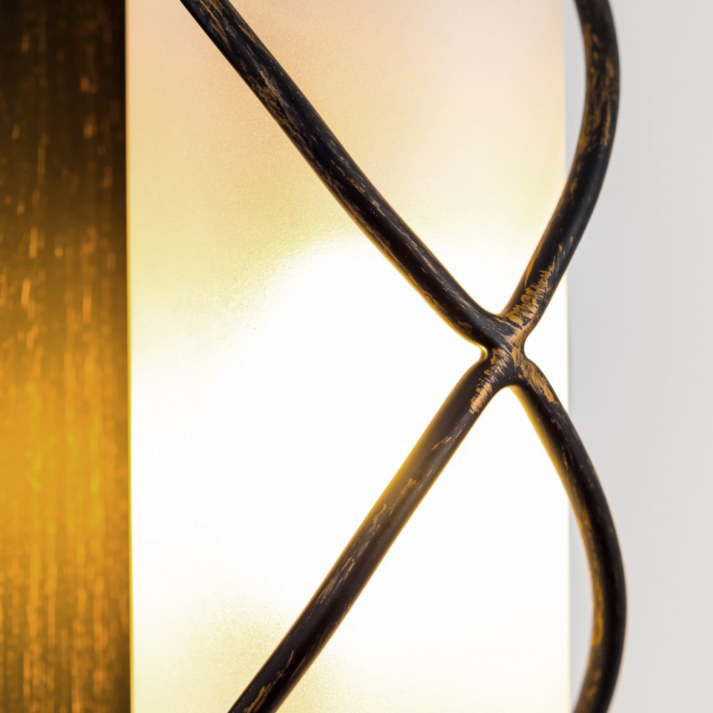 Nahaufnahme einer Wandlampe mit Milchglas und goldfarbenen Metallakzenten, vor weißem Hintergrund.