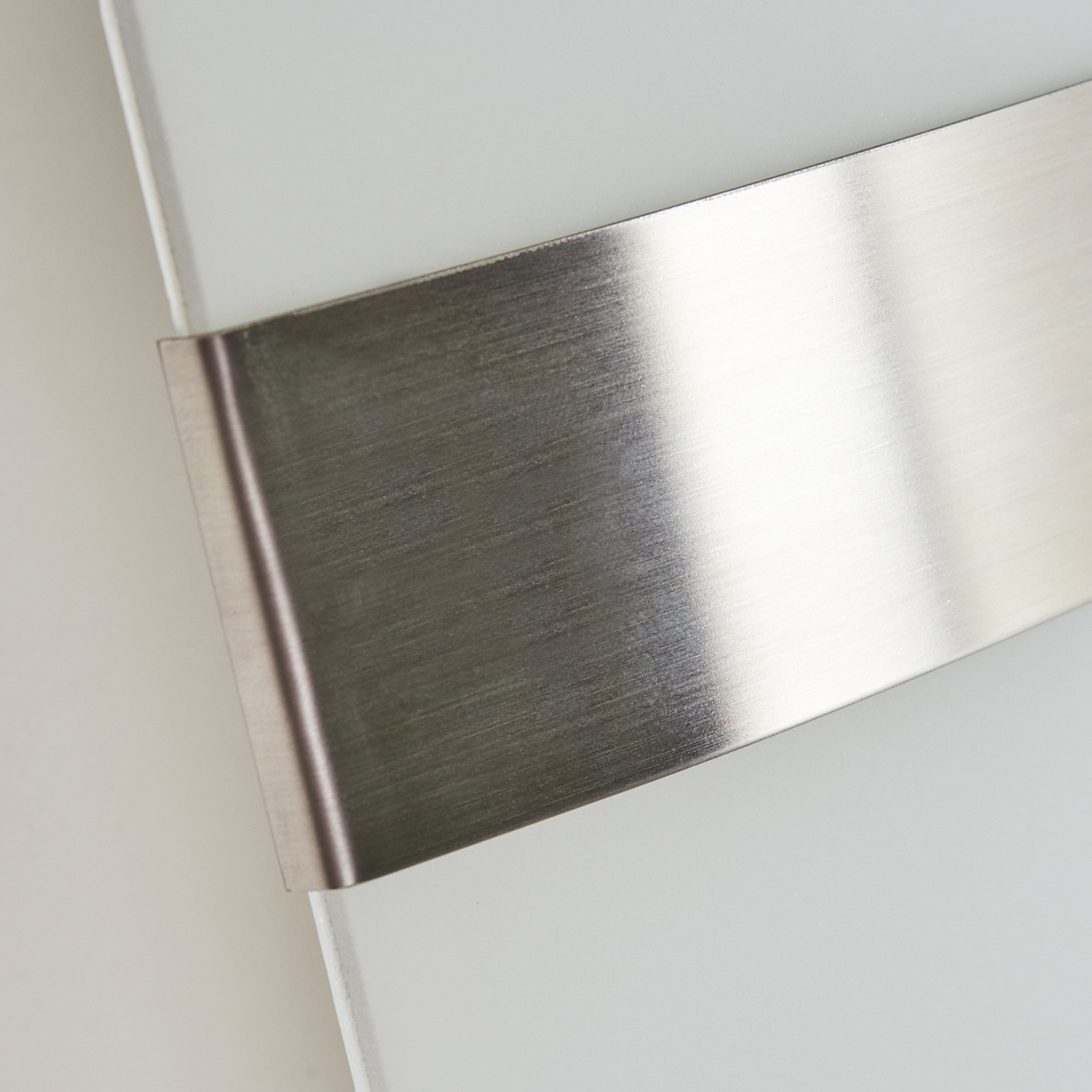 Nahaufnahme einer Wandleuchte mit mattierter Glasfront und Metallstreifen.