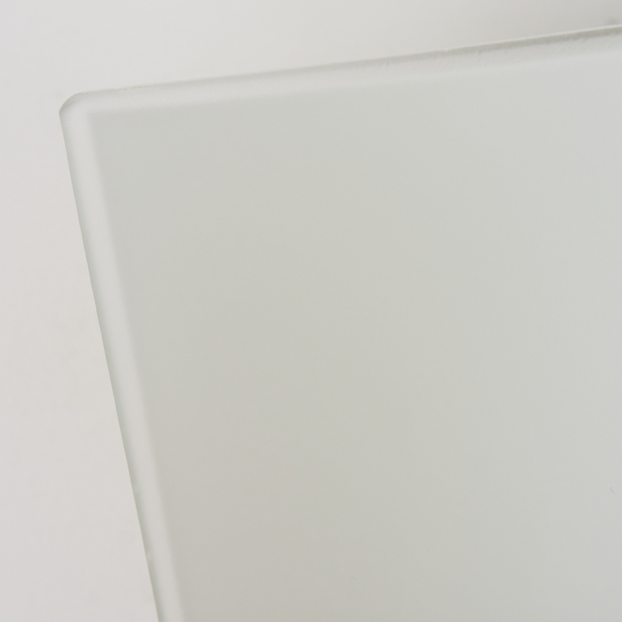 Eine Nahaufnahme einer durchscheinenden weißen Glasscheibe, die ihre mattierte Textur und ihr minimalistisches Design zeigt.