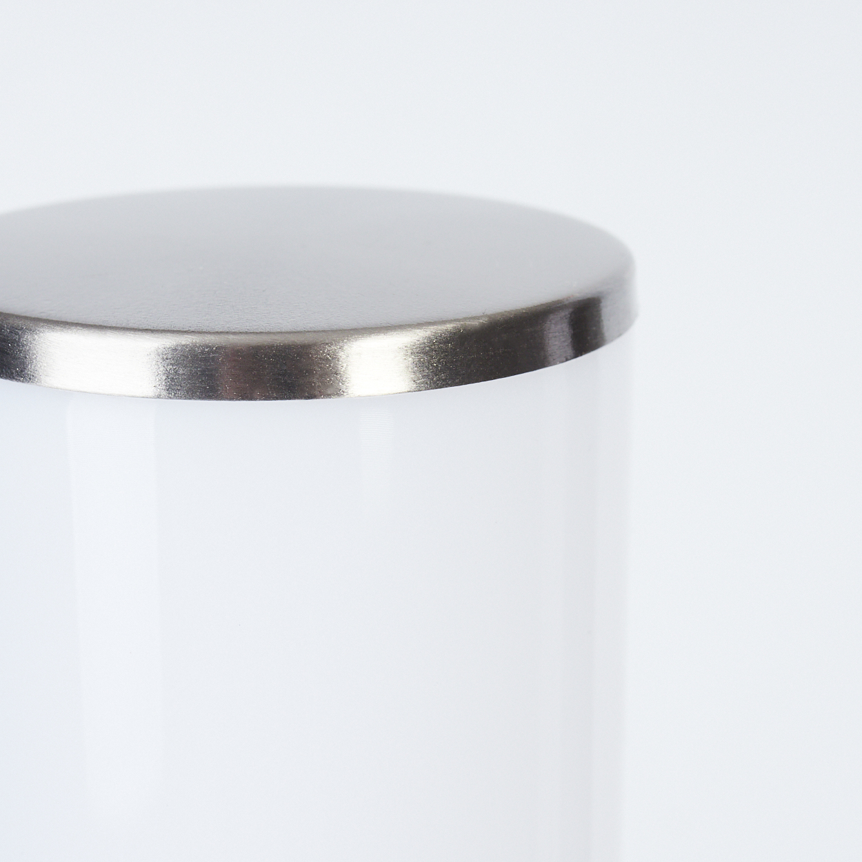 Ein weißes zylindrisches Objekt mit glänzendem Metallaufsatz. Das Objekt ist schlicht und einfach im Design.