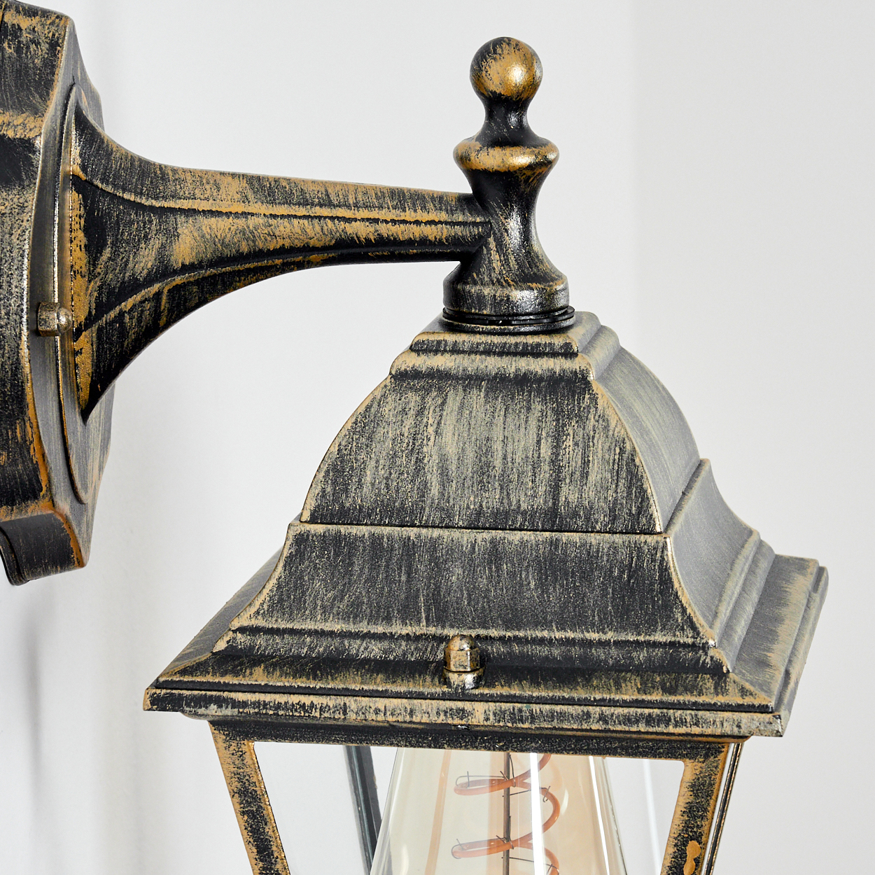 Wandleuchte mit schwarzem und goldenem Finish, Nahaufnahme. Die Glühbirne ist sichtbar.