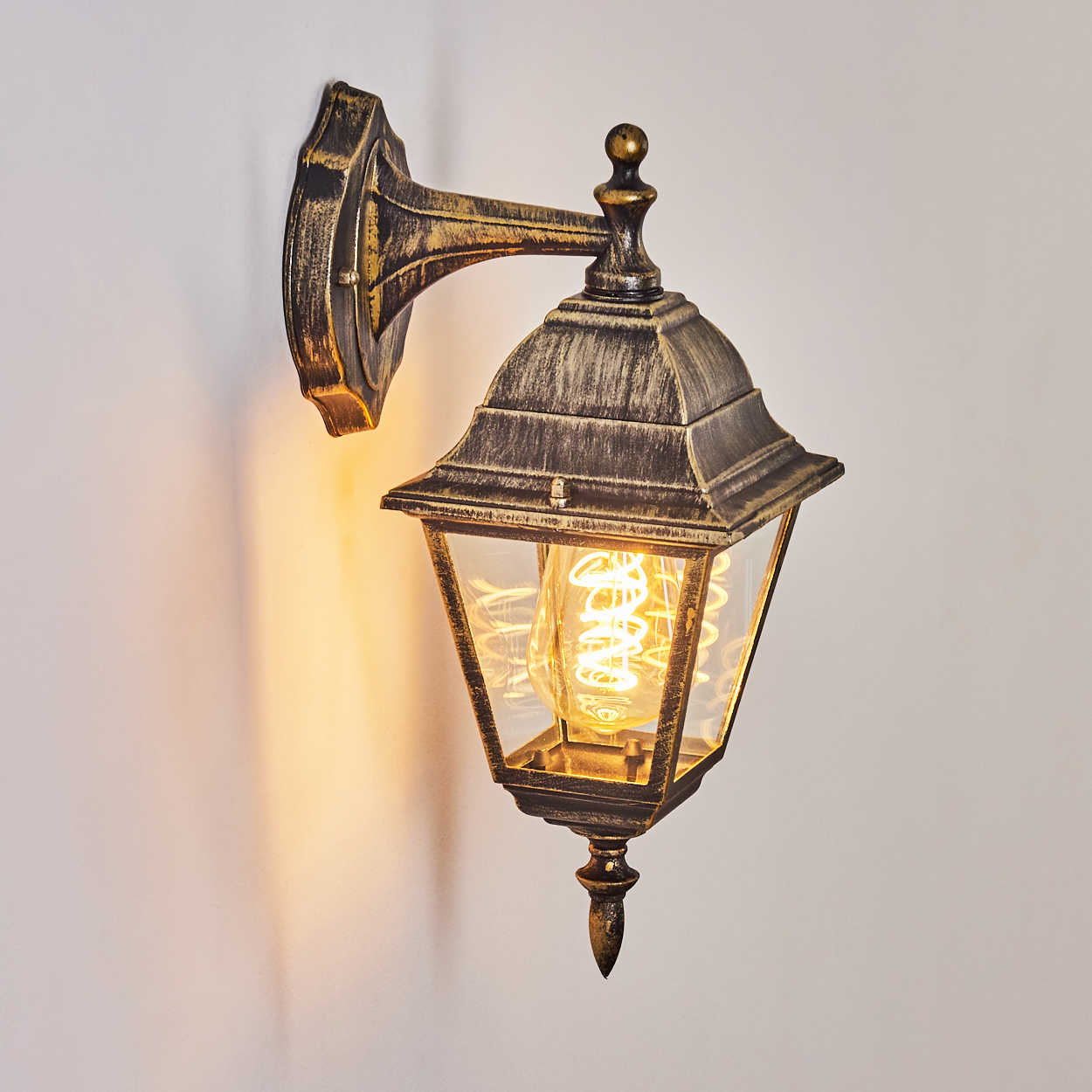 Eine Wandlampe im Vintage-Design. Sie hat ein Glasgehäuse und ist mit einer Glühbirne im alten Stil beleuchtet.