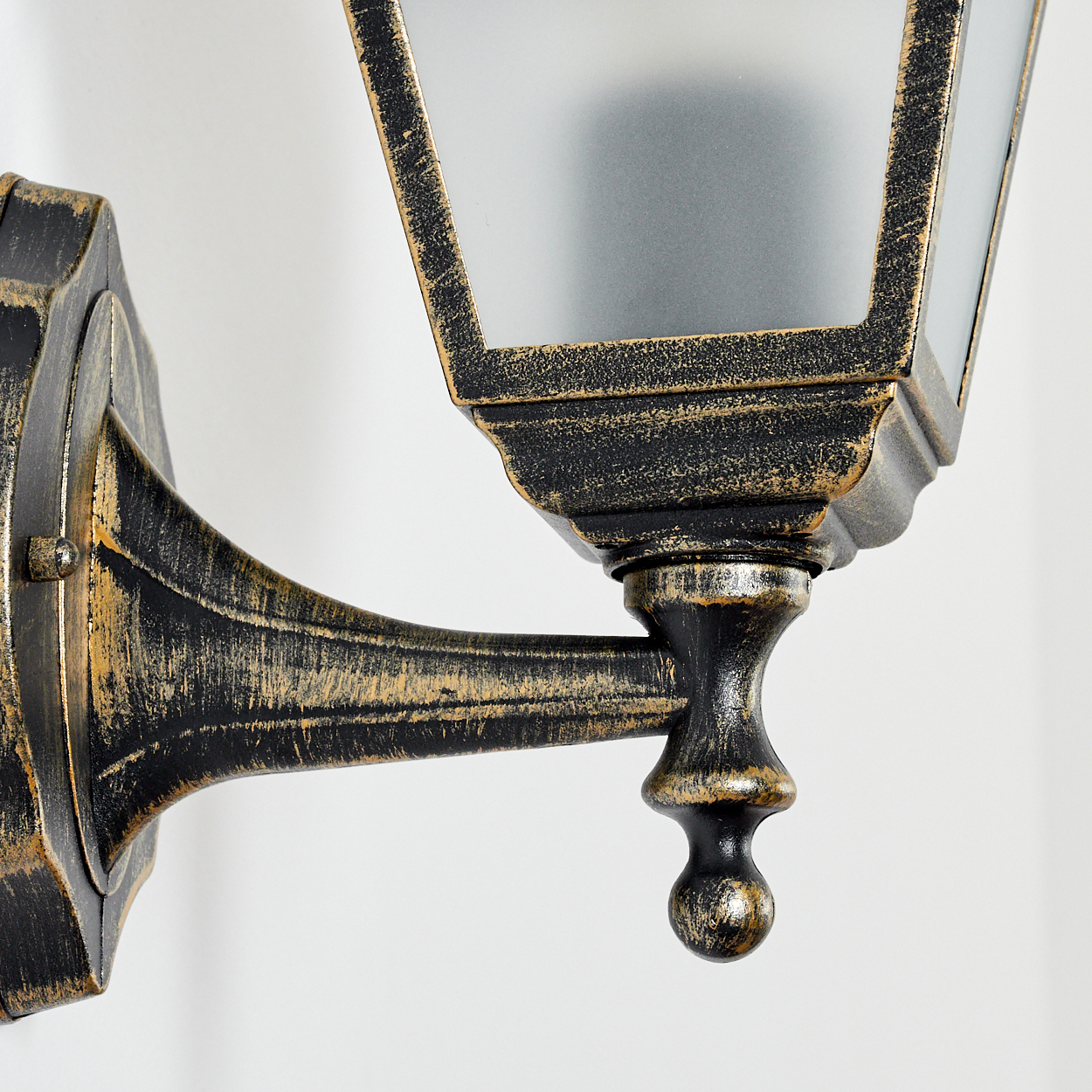 Nahaufnahme einer goldfarbenen Wandlampe, die Details des Designs und der Struktur der Lampe zeigt.