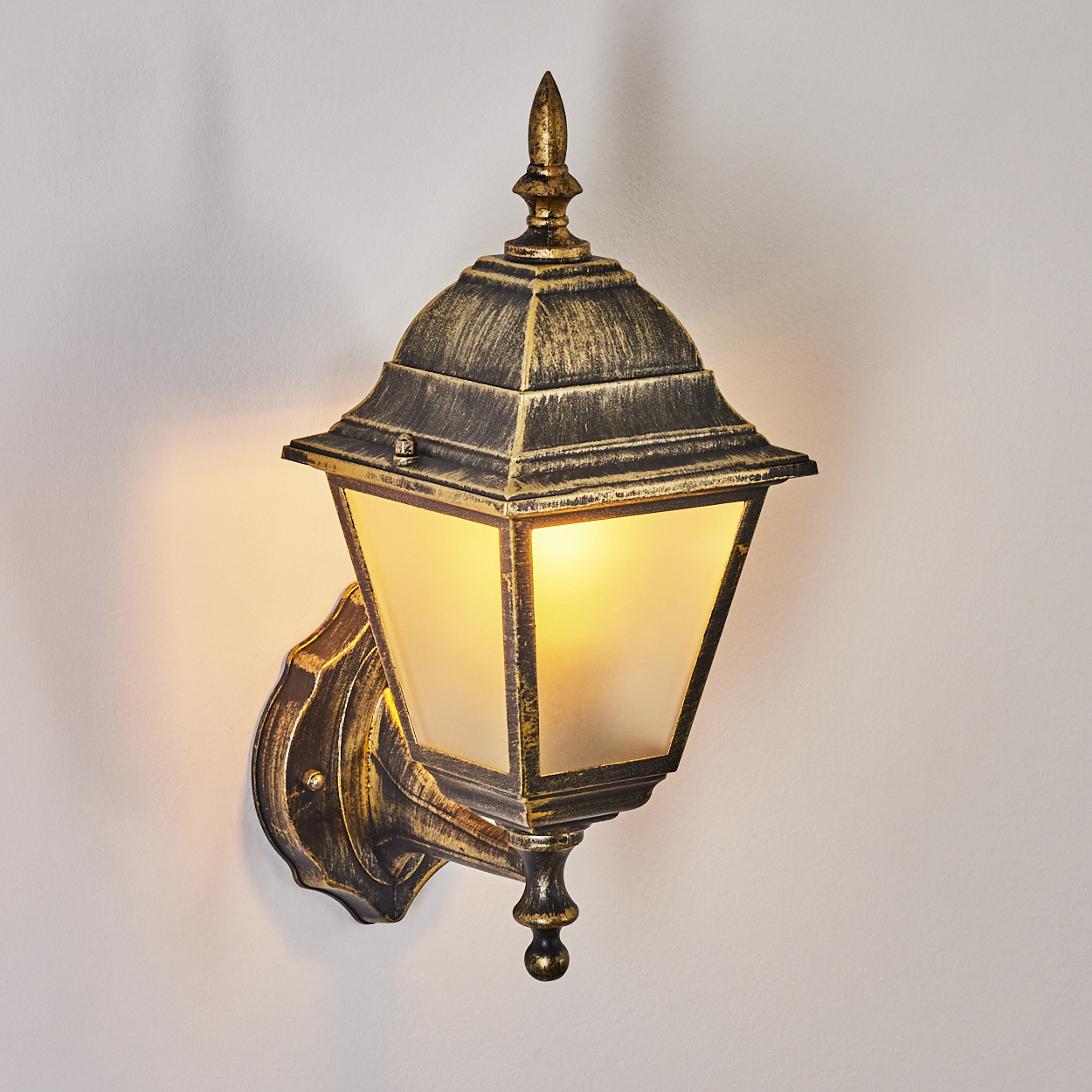 Goldfarbene Wandlampe, beleuchtet, an einer weißen Wand. Antikes Design.