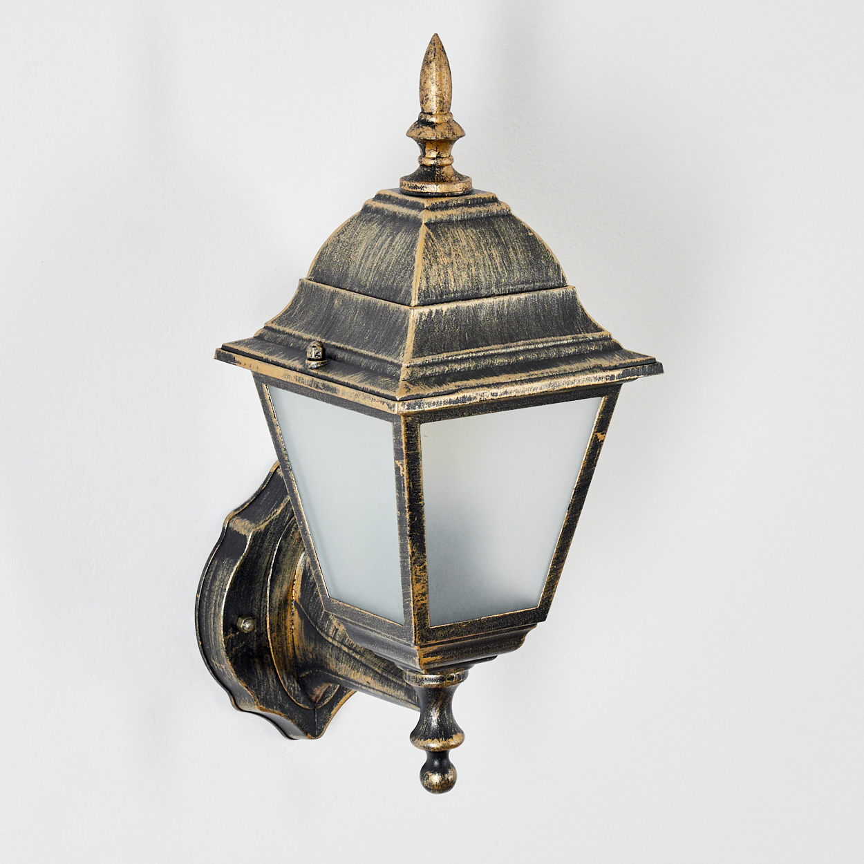 Goldfarbene Wandlampe an weißer Wand, mit Milchglasschirm. Die Lampe ist beleuchtet.