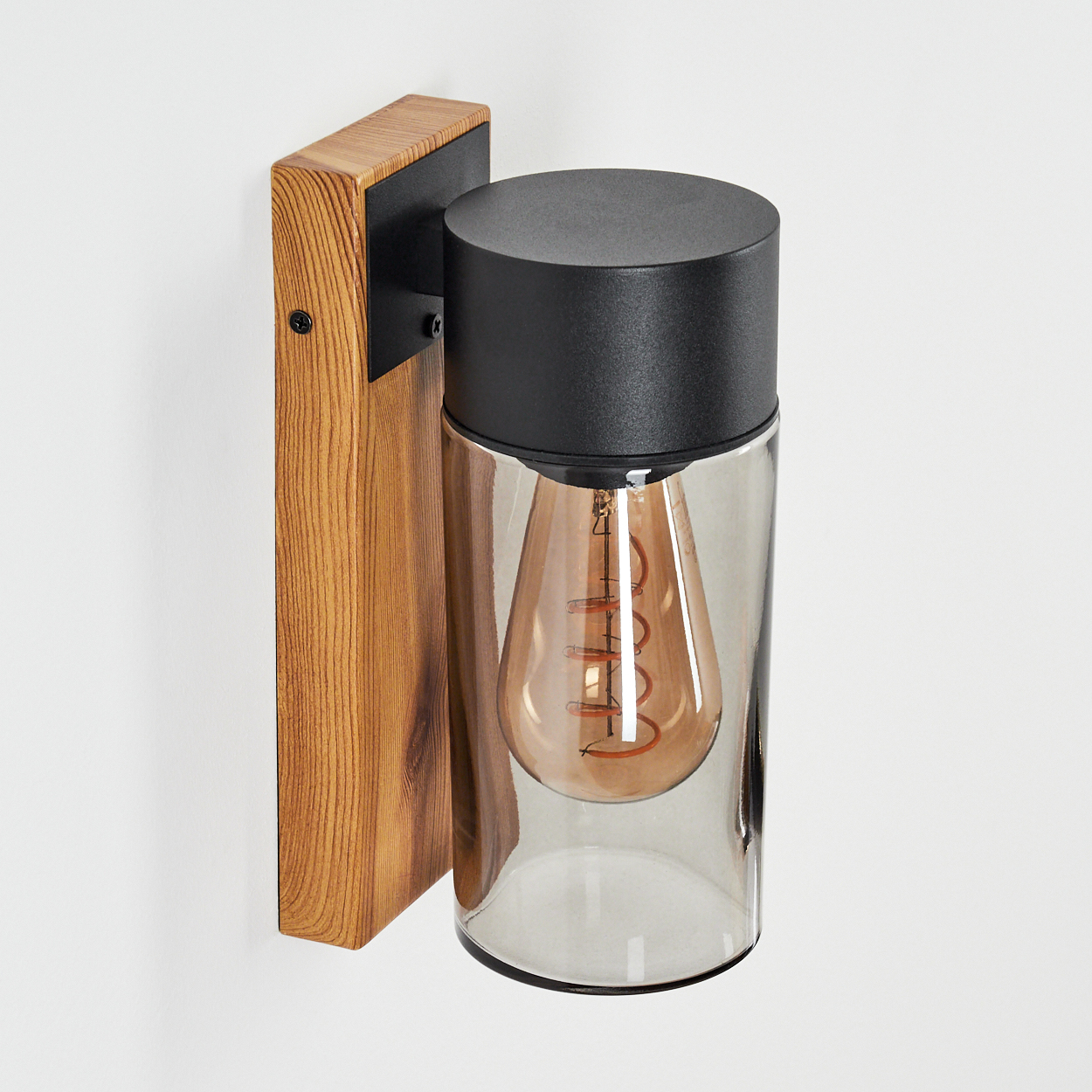 Wandleuchte mit Holzsockel und schwarzem Aufsatz. Transparenter Glaskörper mit sichtbarer Glühbirne.