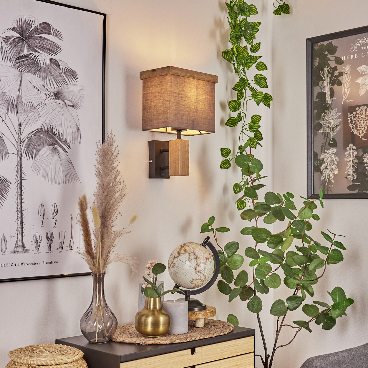 Eine Wandleuchte mit Lampenschirm, Globus und einigen Blumen auf einem Schrank.