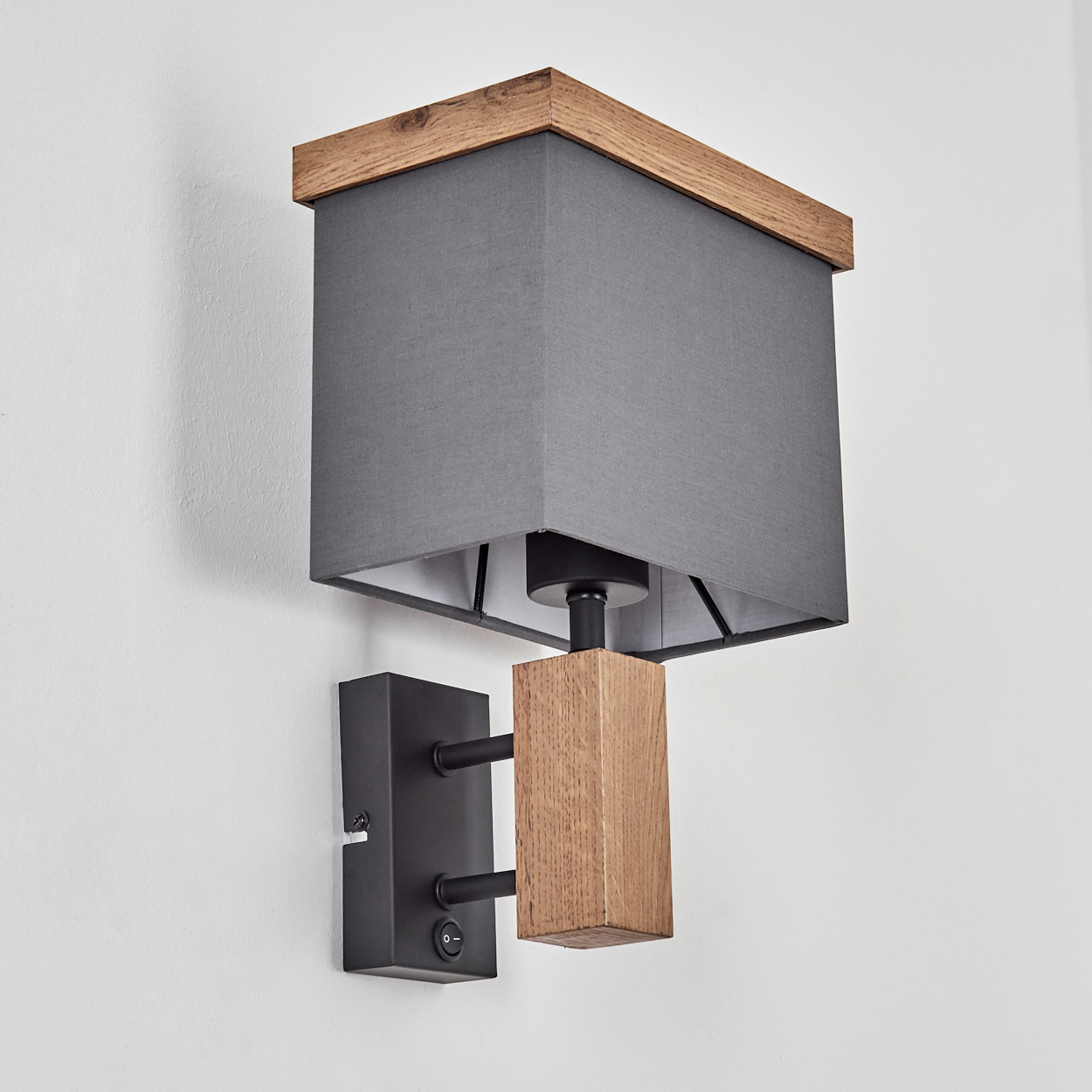 Eine Wandleuchte mit grauem Schirm und Holzelementen. Sie hat einen schwarzen Sockel und einen Ein/Aus-Schalter.