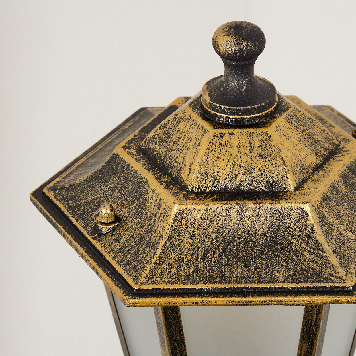 Nahaufnahme einer schwarzen und goldenen Außenlampe, die die strukturierten Details der Metallarbeiten zeigt.