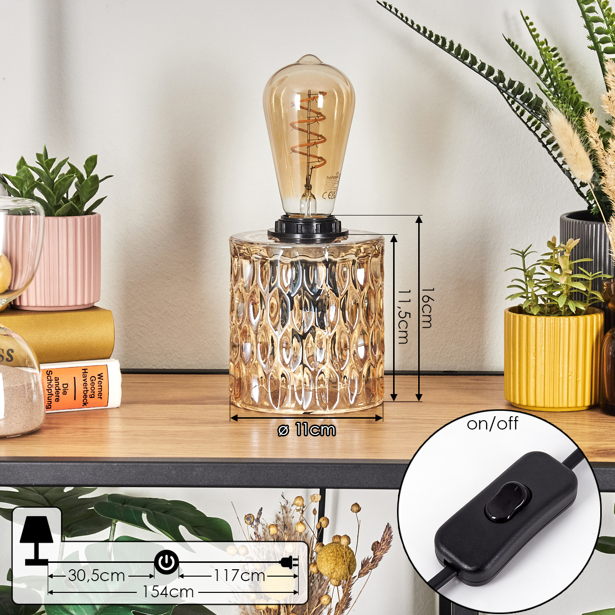 Eine Lampe mit strukturiertem goldenen Sockel und sichtbarer Glühbirne steht auf einem Regal mit Büchern und Dekorationen.