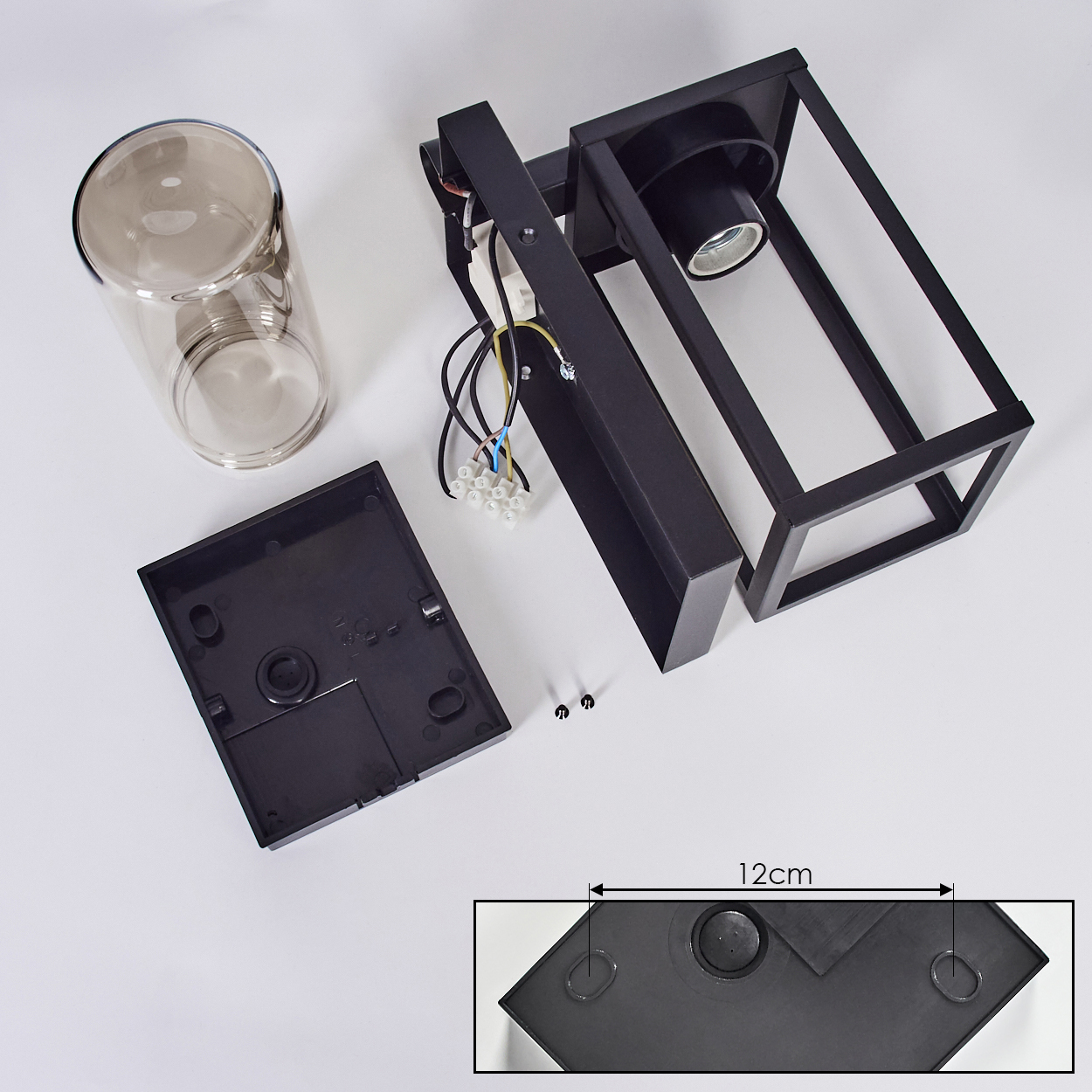 Zerlegte schwarze Wandlampenkomponenten mit einem Glaszylinder und einer Nahaufnahme der Montagebasis.