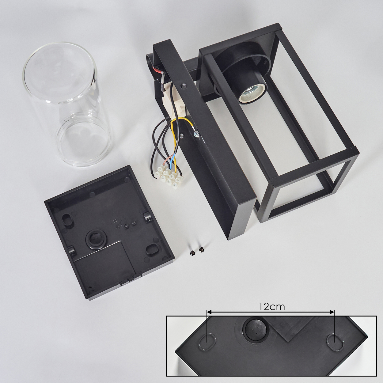 Zerlegte Wandlampe mit schwarzem Rahmen, Glaszylinder und Basisteilen. Die Basis misst 12cm.