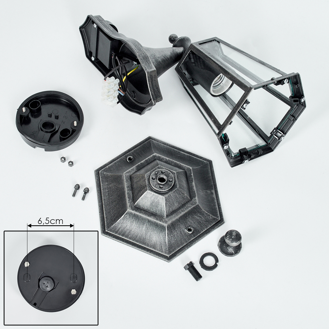 Demontierte Lampe. Teile umfassen eine Basis, Schrauben und eine Leuchte mit metallischem Finish.