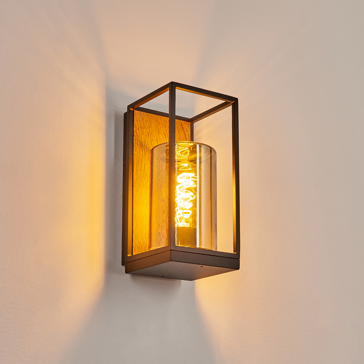 Wandlampe mit schwarzem Rahmen, Holzrückwand und Glaszylinder mit Glühbirne.