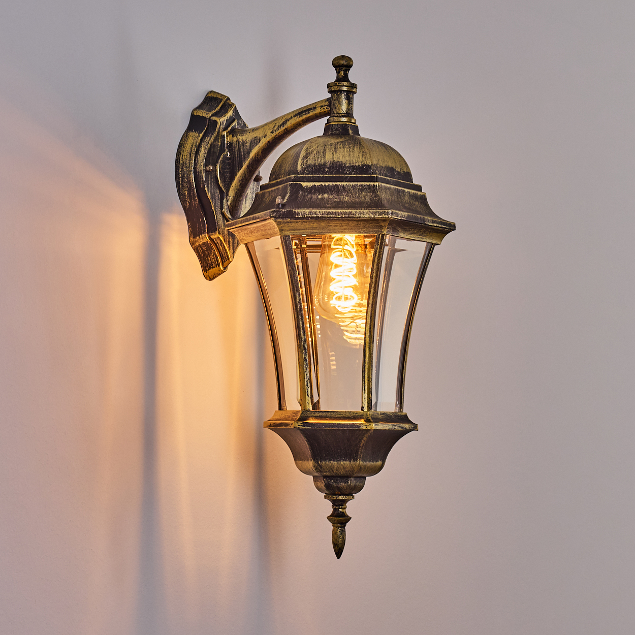 Eine Außenwandleuchte mit dekorativem Design, die ein warmes Licht auf die Wand wirft.