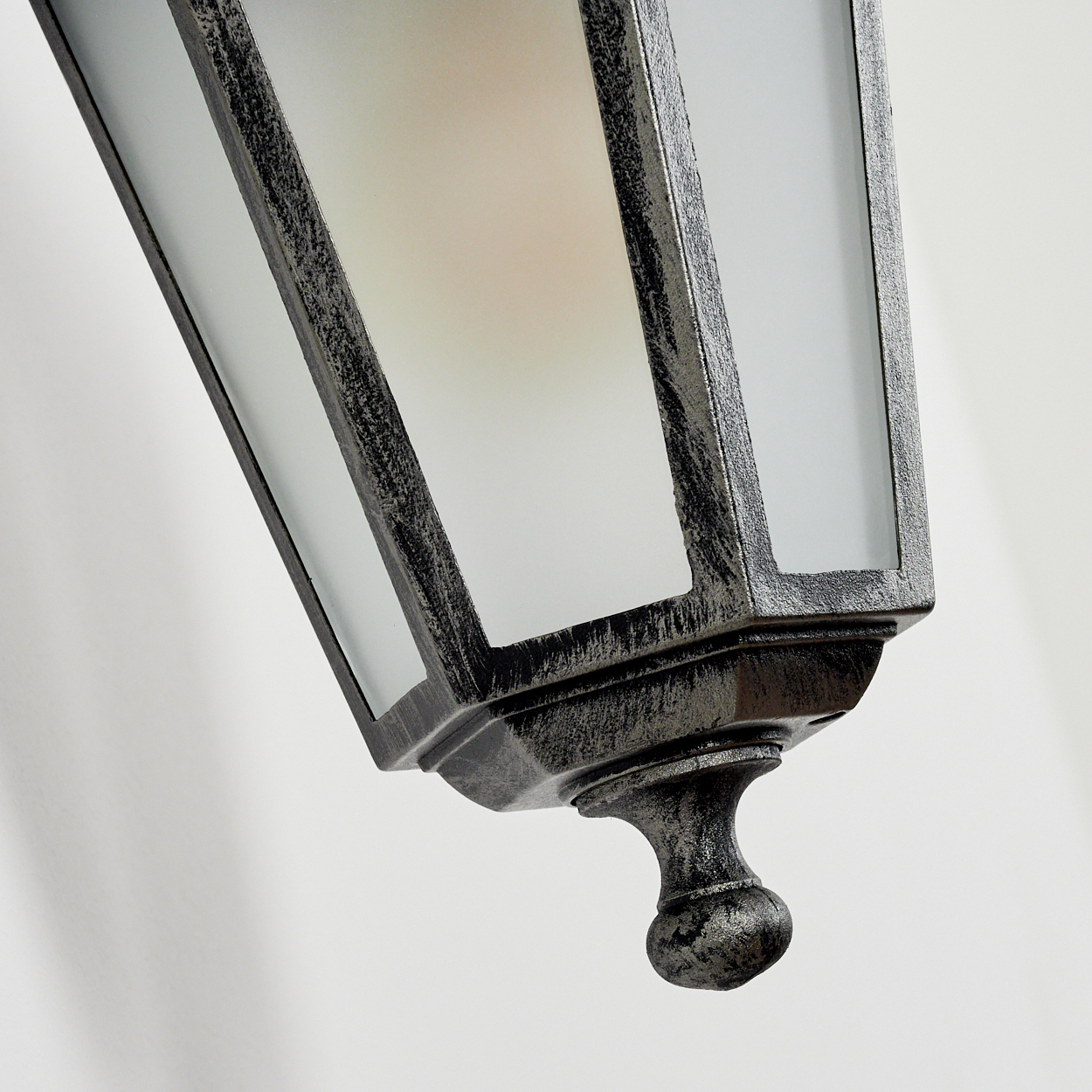 Nahaufnahme des Milchglases einer Außenwandleuchte. Die Lampe hat eine metallische Oberfläche und eine sichtbare Glühbirne. Weißer Hintergrund.