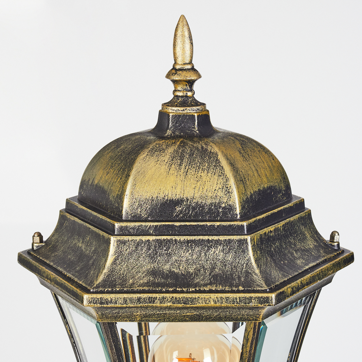 Nahaufnahme der Oberseite einer gold-schwarzen Straßenlaterne mit Glühbirne.