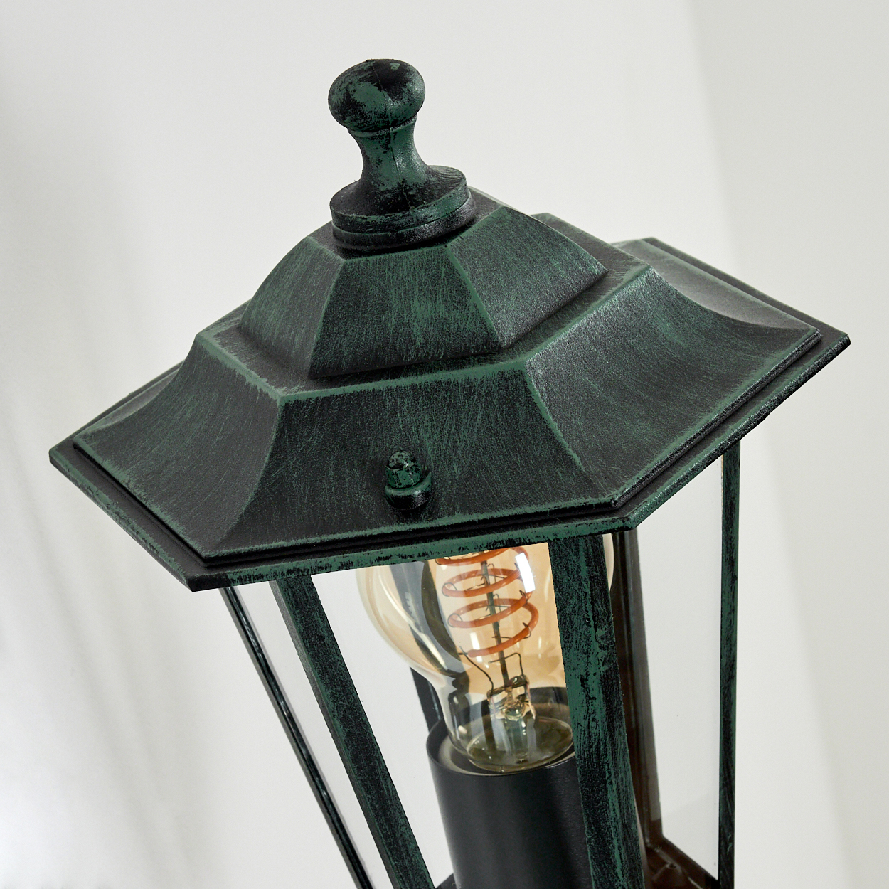 Nahaufnahme einer grünen Wandlampe mit Glühbirne. Weißer Hintergrund.