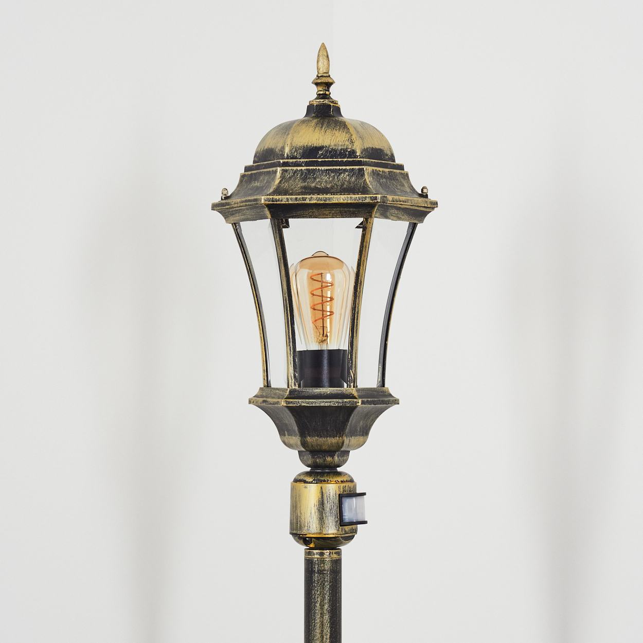Außenlampenpfosten. Die Lampe hat eine dekorative Spitze und eine Glühbirne. Ein Bewegungssensor ist enthalten.