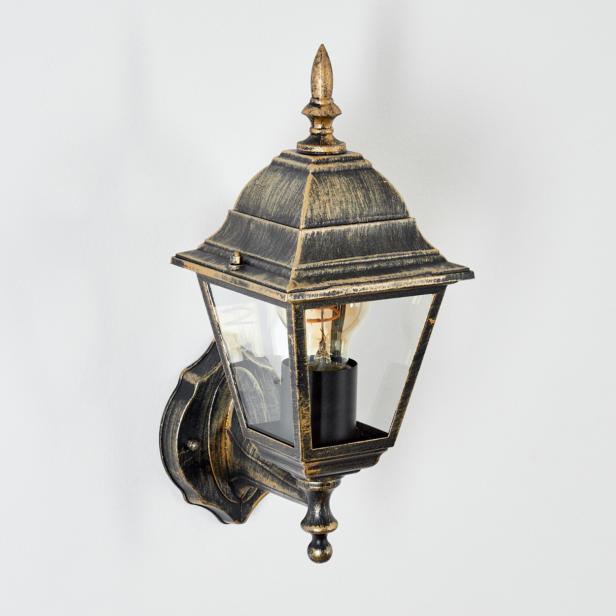 Außenwandlampe, schwarz-gold, mit leuchtender Glühbirne, auf Weiß. Winkelansicht.