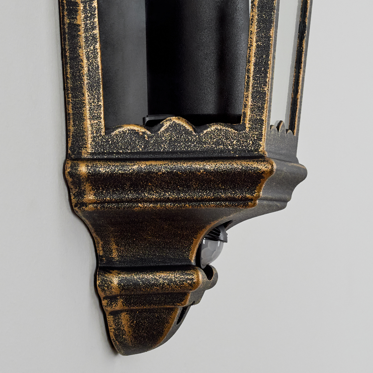 Nahaufnahme des Sensors einer Außenlampe. Schwarz und Gold mit hellem Hintergrund.