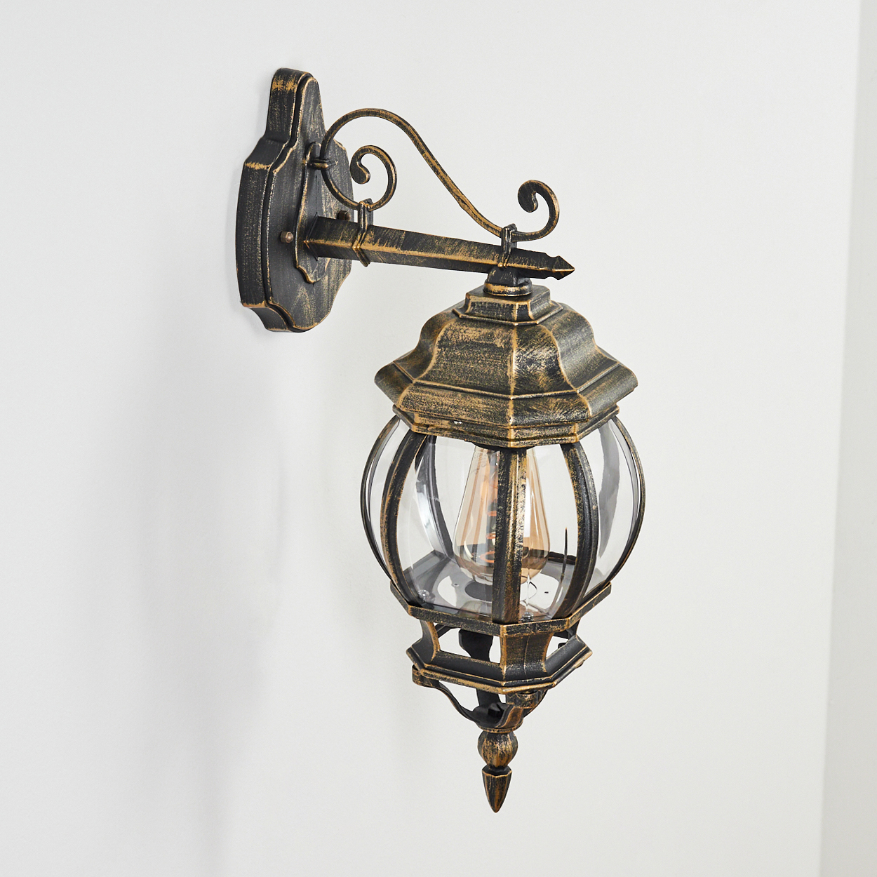 Goldene Metall-Wandleuchte mit Glühbirne, das Licht ist an.