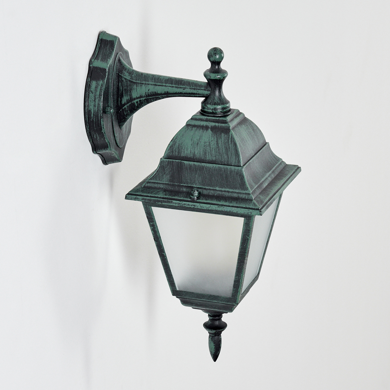 Eine Außenlampe mit grünem Metallrahmen und Milchglas, an einer weißen Wand montiert.