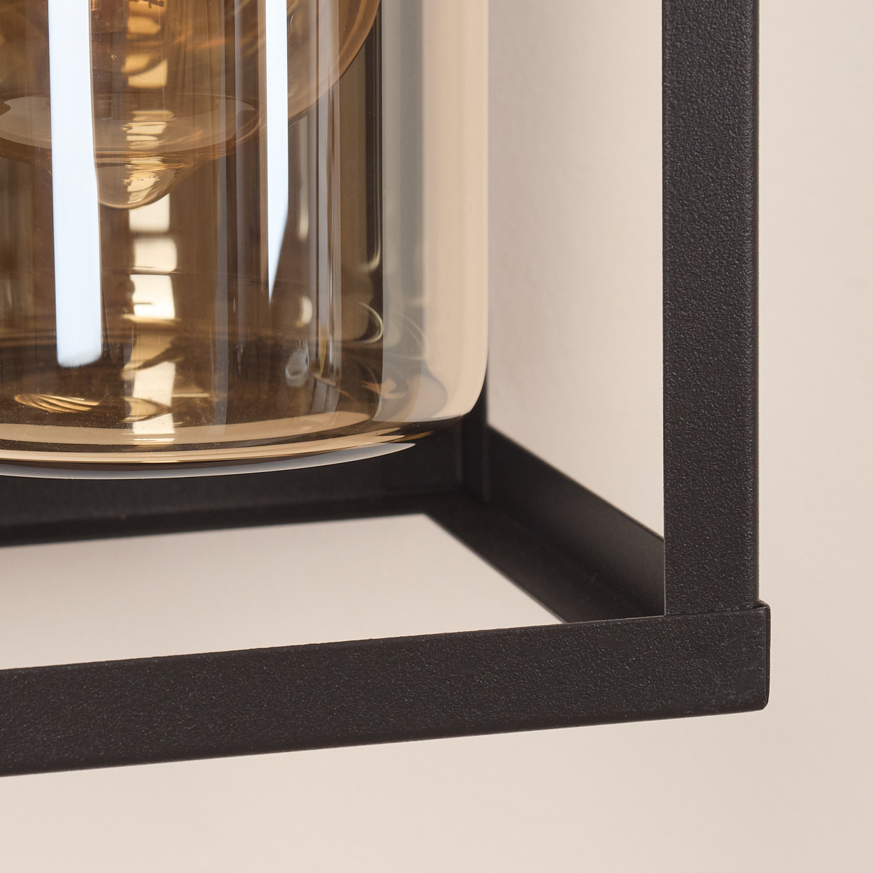 Nahaufnahme des schwarzen Metallrahmens einer Lampe mit einem Glaseinsatz.