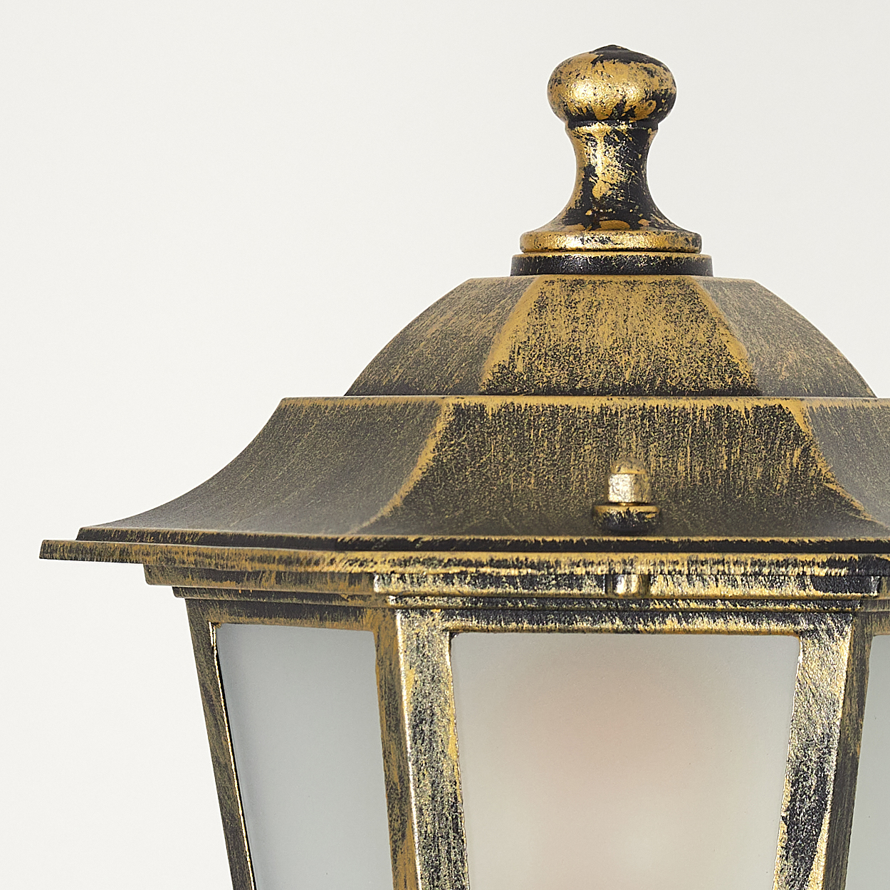 Nahaufnahme einer goldenen und schwarzen Außenlampe. Die Lampe hat eine dekorative Spitze und klare Glasscheiben.