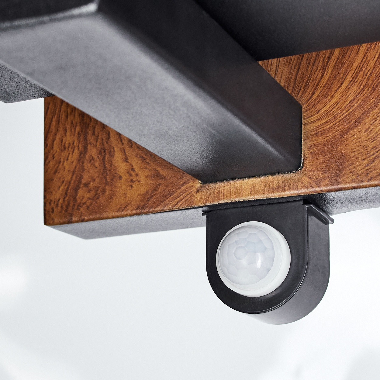 Nahaufnahme eines schwarzen Sensors auf einer Holzoberfläche. Der Sensor ist weiß und kreisförmig.