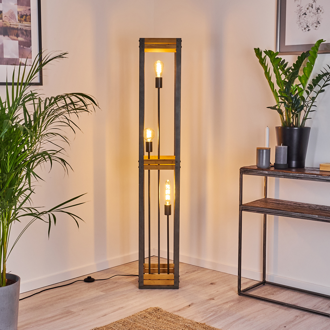 Eine hohe Stehlampe mit Edison-Glühbirnen, in einer Ecke platziert, mit Pflanzen und dekorativen Gegenständen drumherum.